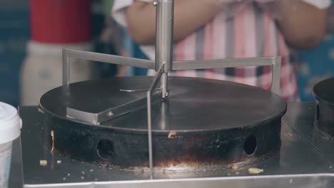 woman waits for metal crepe maker heating in fast food cafe