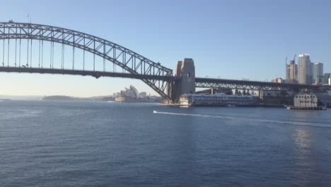 sydney harbour bridge, australia | 4k uhd stunning drone shot of a boat travelling under the harbour bridge at sunrise