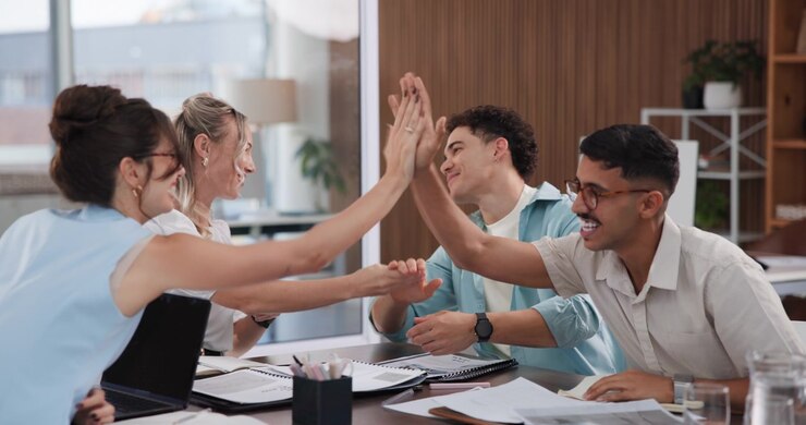 Equipe de Negócios Diversa Comemorando o Sucesso com High Fives em Reunião no Escritório