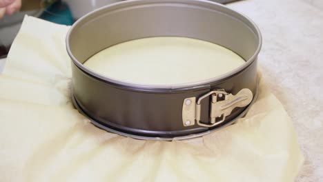 tattooed arms of chef places parchment paper into springform pan