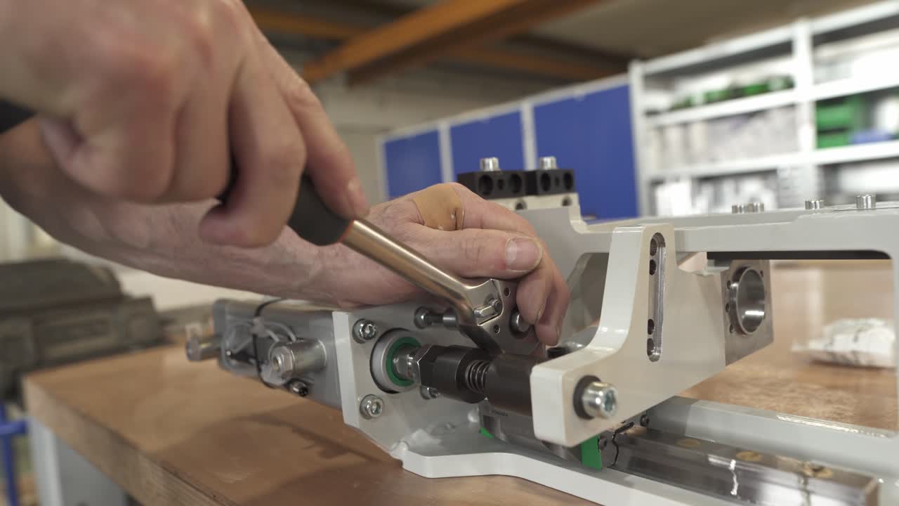 Technician tightening a lead screw assembly on a precision linear actuator. Close up of mechanical adjustment of a positioning system in a workshop