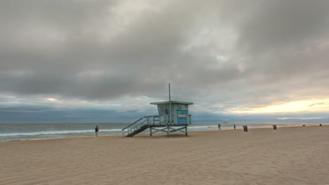 manhattan beach pier lifeguard tower with people on a cloudy sunset in california, usa