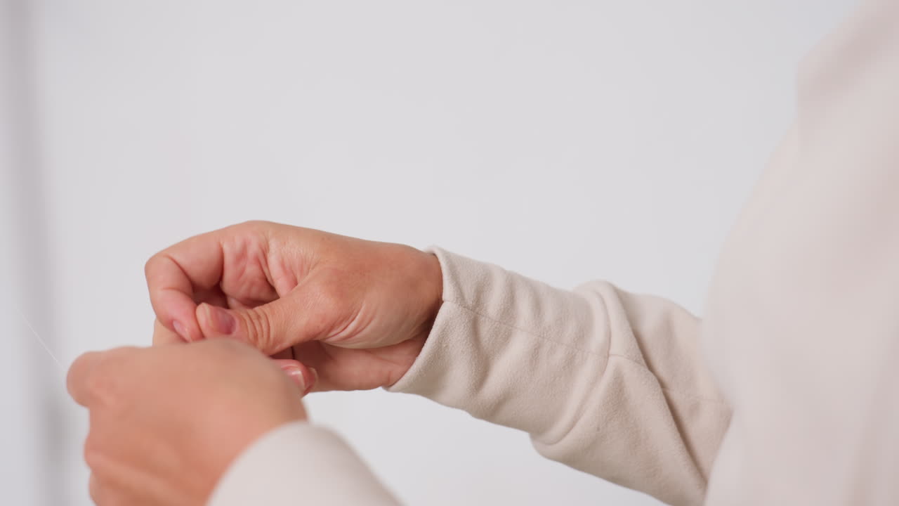 Hand view of woman tightening twine and trimming ends with steady technique, focusing on manual detail and calm precision in bright minimal workspace, highlighting professional finishing tasks