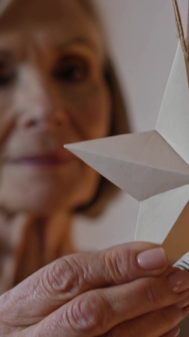 Video verticale: Telecamera che si allontana, donna anziana con maglia a coste che ruota e studia la superficie di una stella