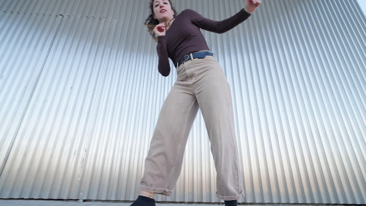 Young woman dancing contemporary urban style against metal wall