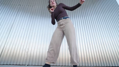 young woman dancing contemporary urban style against metal wall
