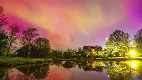 el lapso de tiempo de la aurora boreal cambiando colores sobre una casa serena en el lago por la noche