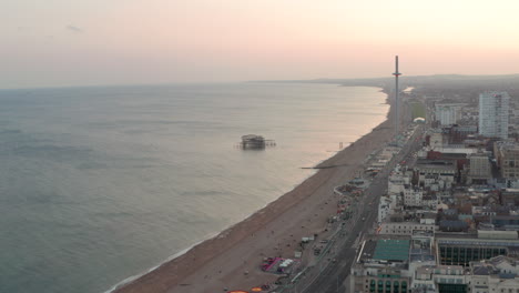 tiro aéreo en círculo sobre el frente marítimo de west brighton al anochecer