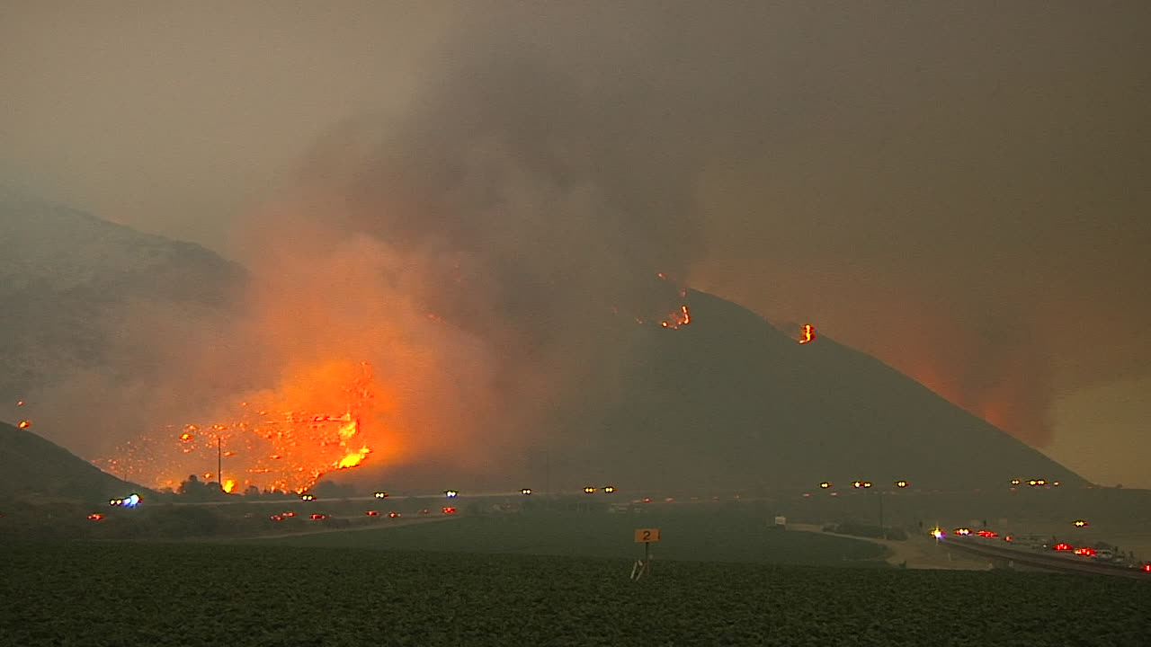 벤추라와 산타바바라 캘리포니아 1 근처의 101번 고속도로 위 언덕에서 밤에 토마스 화재가 타오릅니다.