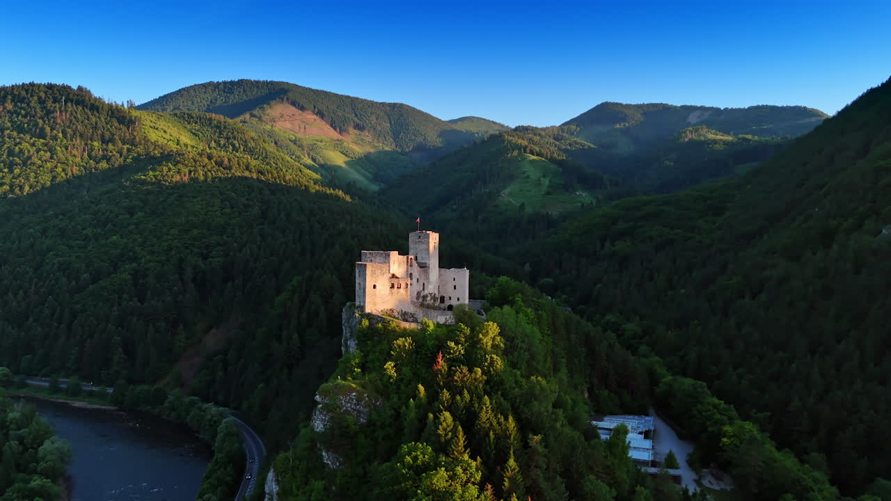Mountain covered with lush forests with a castle on top. Slovakia nature and landmarks from drone footage. Tatra mountains at backdrop