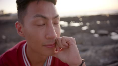 Happy-asian-man-looking-away-at-beach,-slow-motion