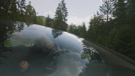 Black-dressed-young-man-driving-in-a-forest-mountain-road