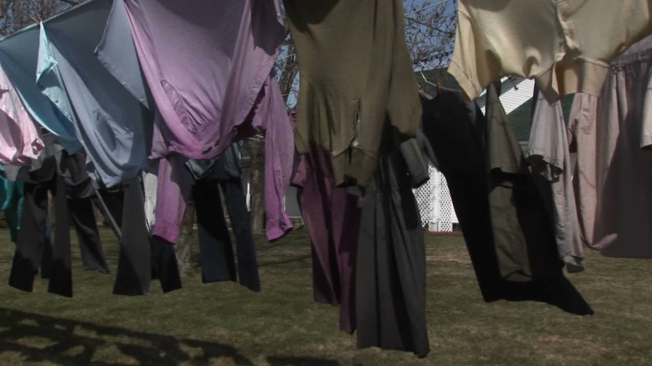 화려한 셔츠와 어두운 드레스는 바람에 말리기 위해 빨랫줄에 매달려 있다