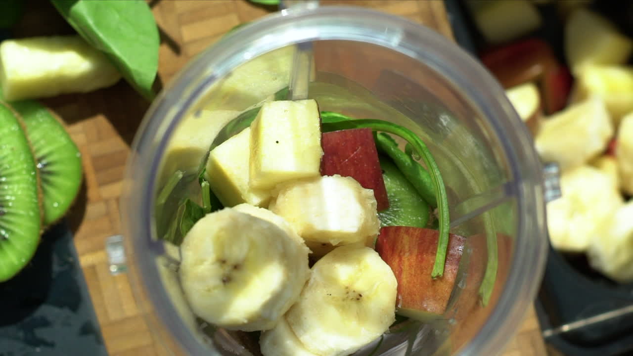 cerca de manos femeninas colocando rodajas de plátano en la licuadora
