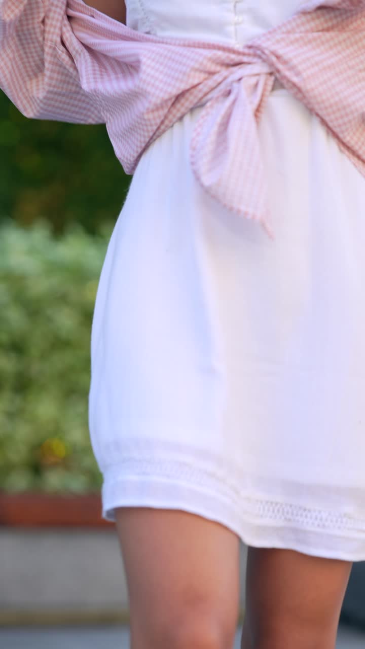 색 드레스와 분홍색 플레이드 셔츠를 입은 젊은 여성