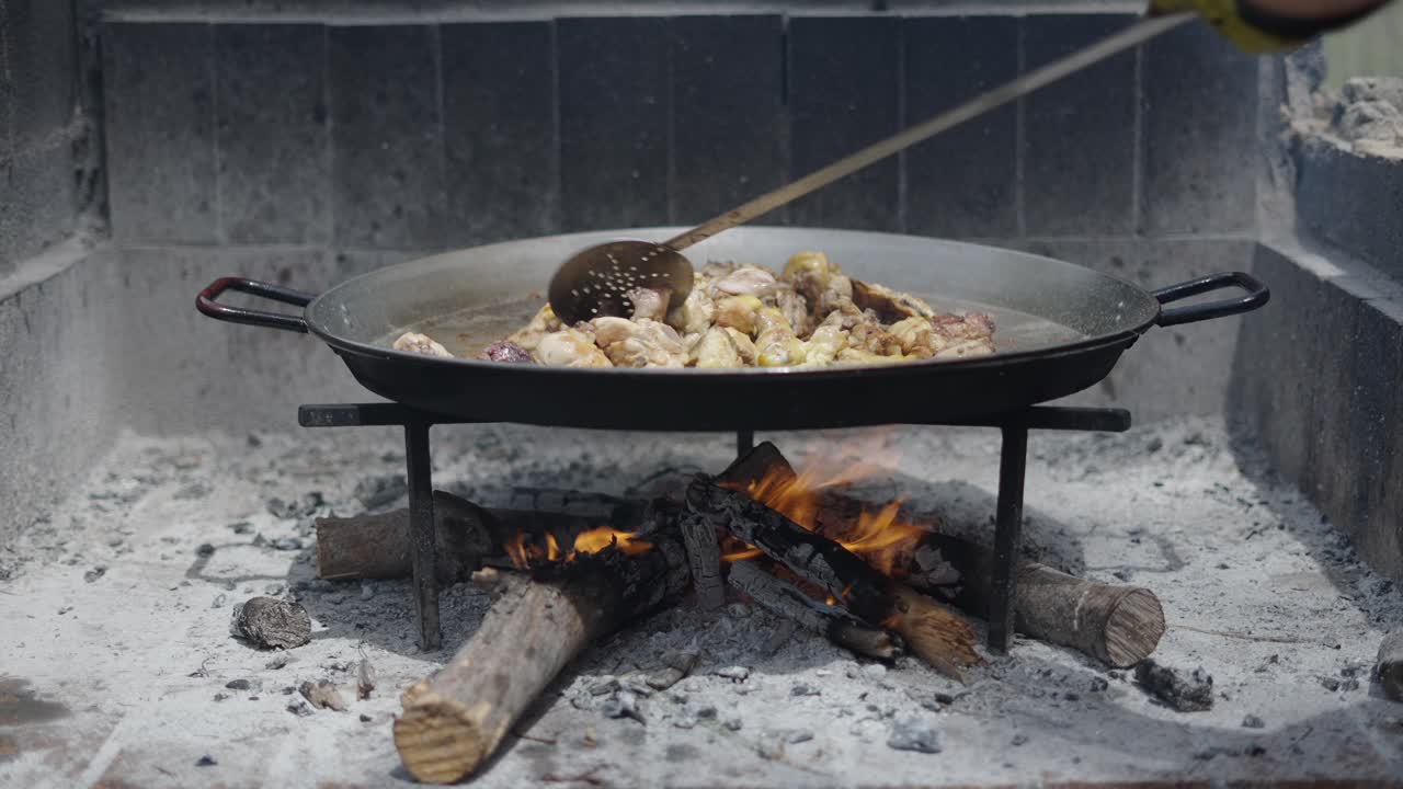 Outdoor Cooking Chicken in a Large Pan Over a Wood Fire