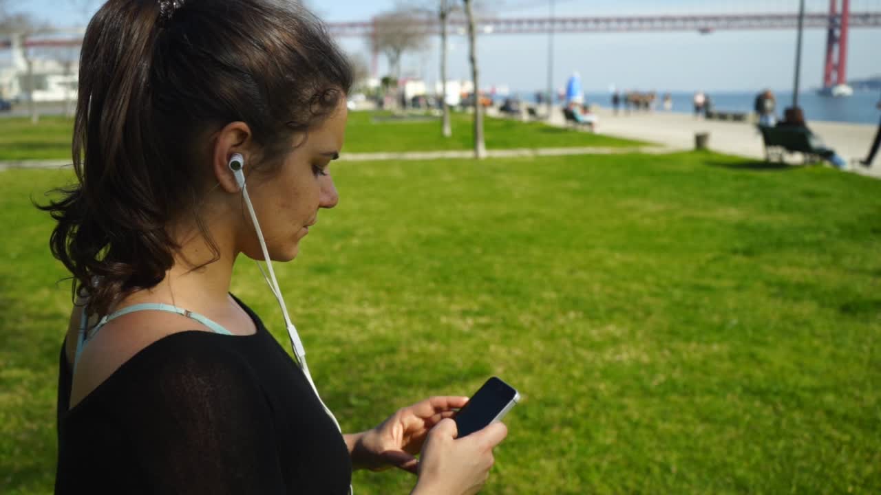 chica atractiva y deportiva usando un teléfono inteligente en el parque