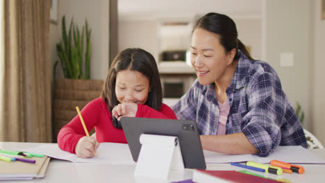 video of happy asian mother and daughter doing homework together