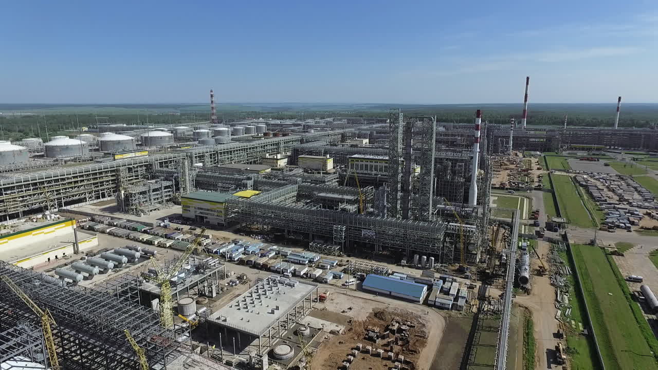 Yeşil bir manzara fonunda büyük bir petrol rafinerisi istasyonunun kuşbakışı görünümü.
