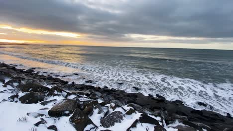 langisandur beach at sunset with waves rinsing black volcanic rocks