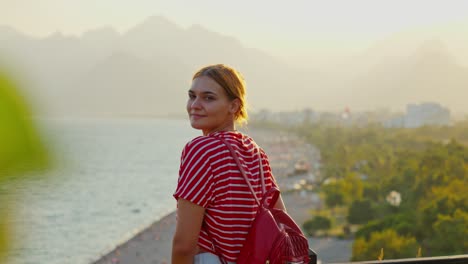 stunnig 4k video of a white ginger girl standing and looking to the beautiful view of the beach and mountains in the background