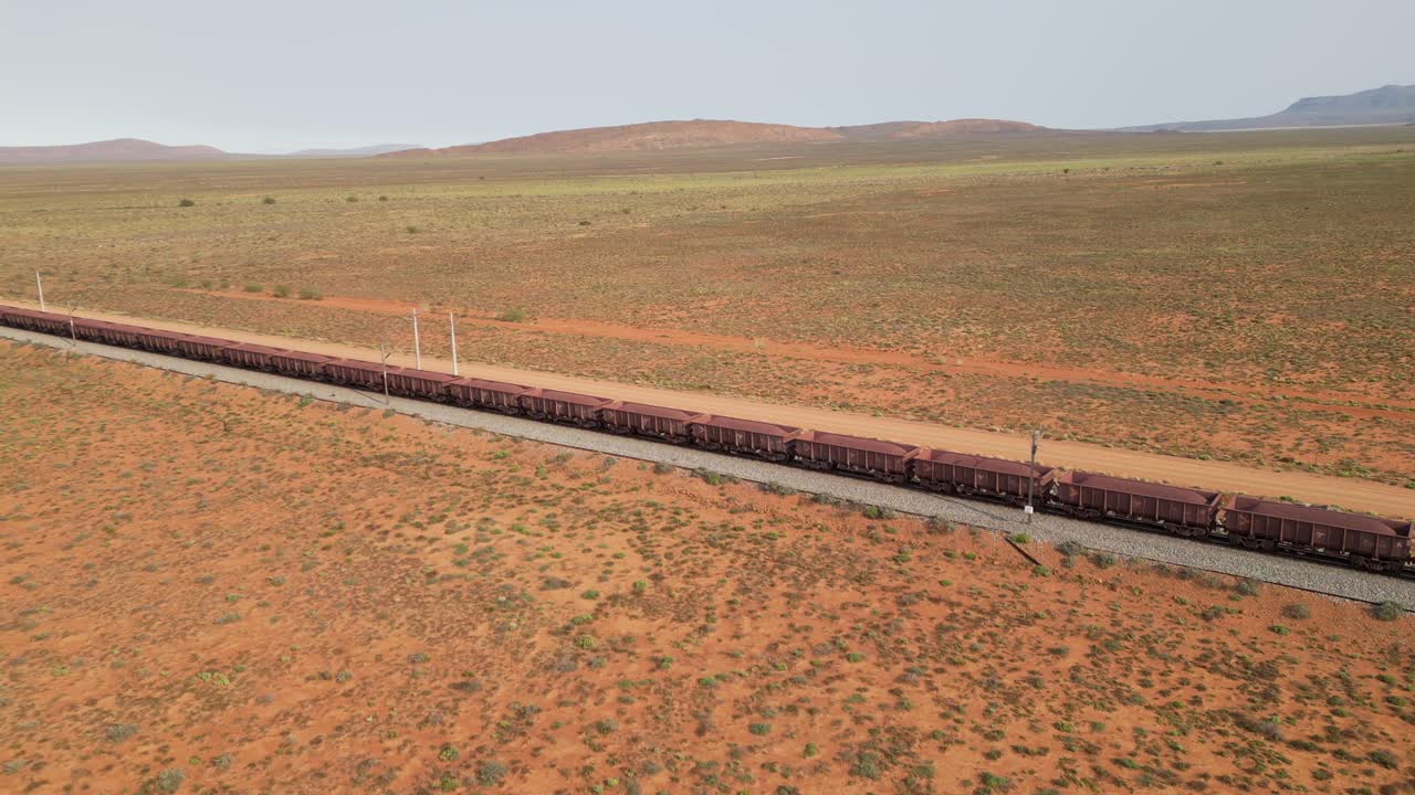 Aerial tracking Train carries iron ore through desert landscape on Sishen to Saldanha Railway