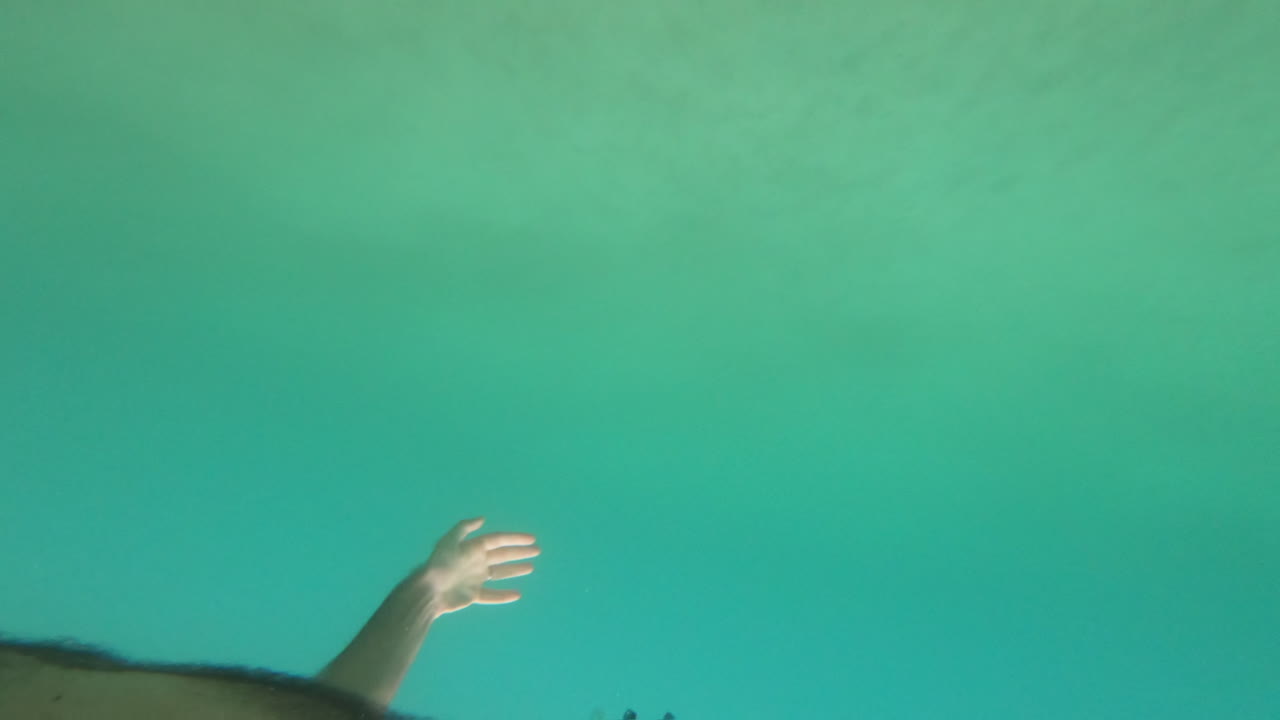Man swimming underwater in the ocean with black goggles