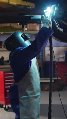 vertical video of caucasian female car mechanic welding car
