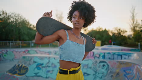 portrait woman skateboarder standing at urban skate park. girl posing skateboard