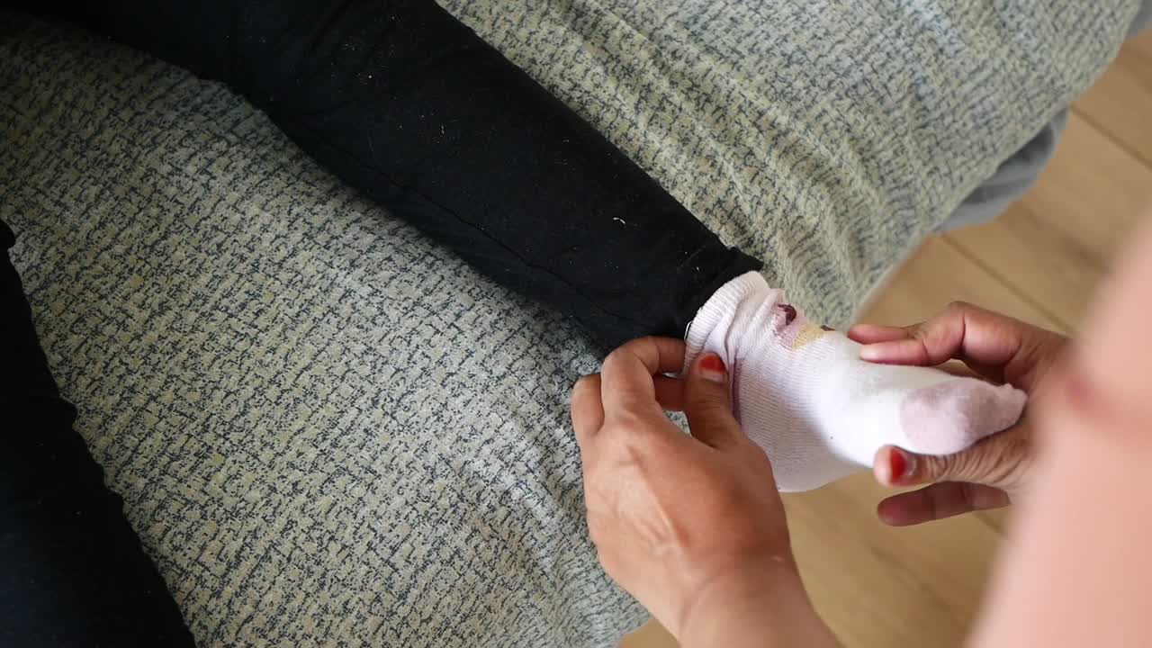 어머니 가 자녀 에게 양말 을 입히고 있다