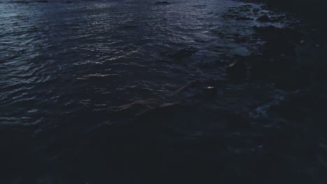 Aerial-view-of-ocean-waves-tilting-up-and-moving-forward-during-dusk-or-dawn