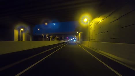 rear facing night driving point of view pov for interior car scene green screen replacement - driving through yellow-lit underpasses and bridges through a major freeway intersection