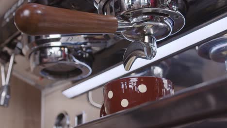 slow-motion closeup of a modern industrial coffee maker in a coffee shop pouring coffee in a cup