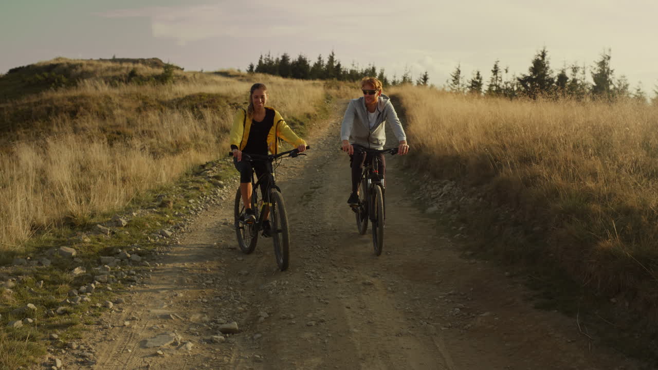 Couple riding sport bicycles on road. Happy cyclists exercising in mountains