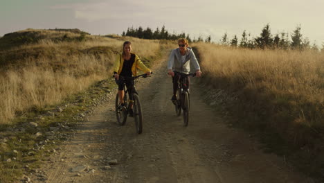 couple riding sport bicycles on road. happy cyclists exercising in mountains