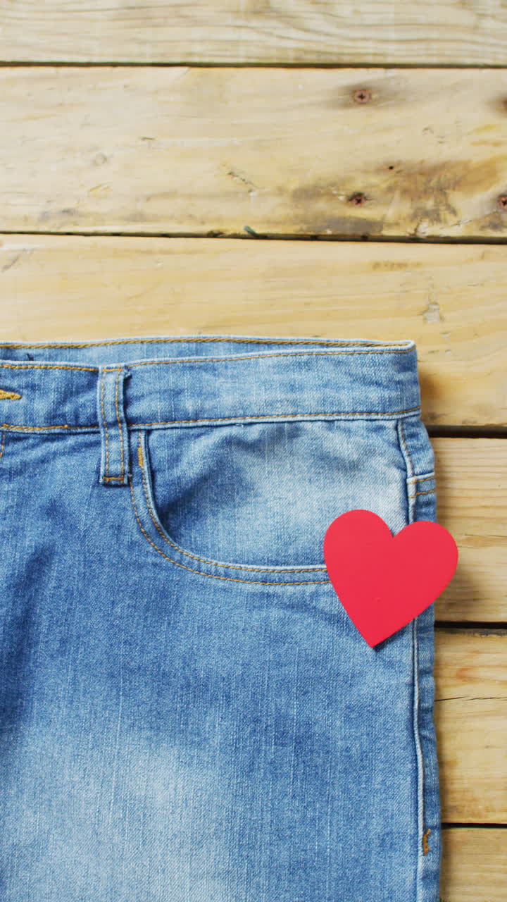 Video verticale di pantaloni in denim con cuore rosso e spazio per il testo su sfondo di legno