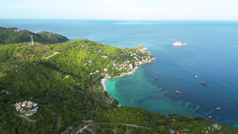 Aerial-shot-of-turquoise-water-in-bay-of-Koh-Tao-Island-with-parking-boats-during-sunny-day,-Thailand---Paradise-on-earth