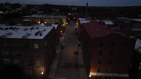 aerial flight over street and junction of american town at night. driving car on road. historic downtown of danville, virginia. dusk scene in small town of usa. orange lighting lanterns. birds eye.
