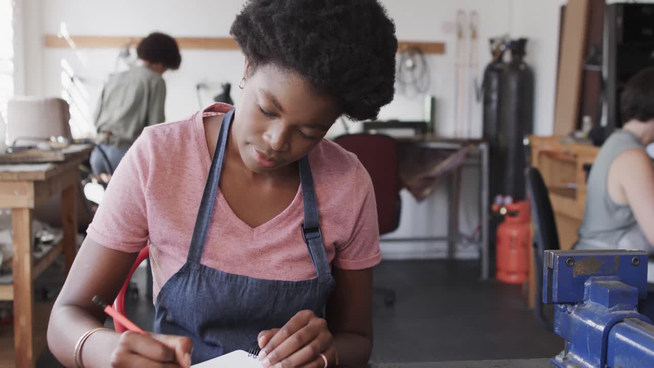 Impegnata lavoratrice afroamericana che disegna il modello di un gioiello in uno studio di gioielleria al rallentatore