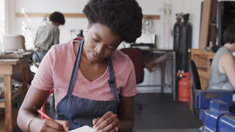 Busy-african-american-female-worker-drawing-design-of-jewellery-in-jewellery-studio-in-slow-motion