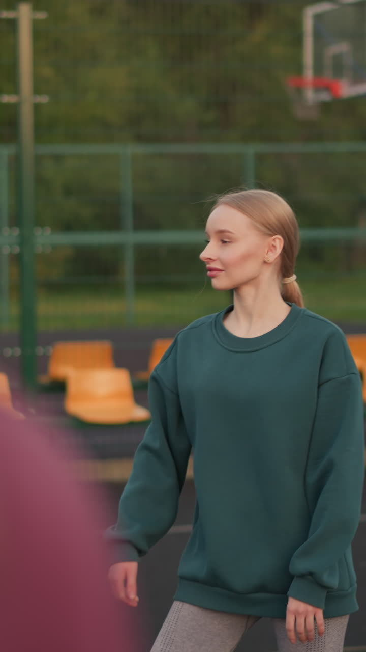 vista de cerca de atrás del instructor dirigiendo al jugador de voleibol cómo servir, con otras personas caminando fuera de la cancha en el fondo, entrenando en acción en la cancha deportiva al aire libre