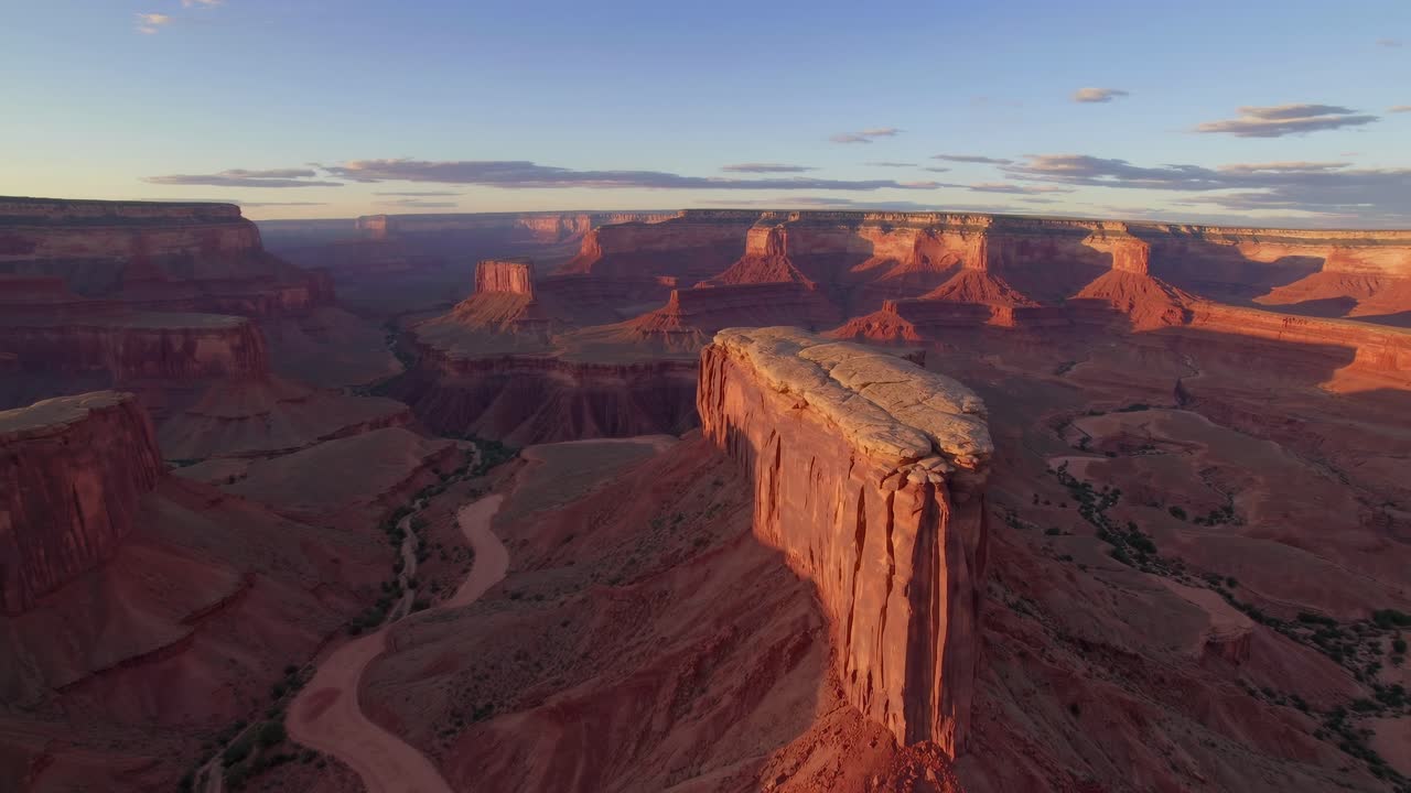 Aerial video capturing vast, sunlit canyons and winding river at sunset