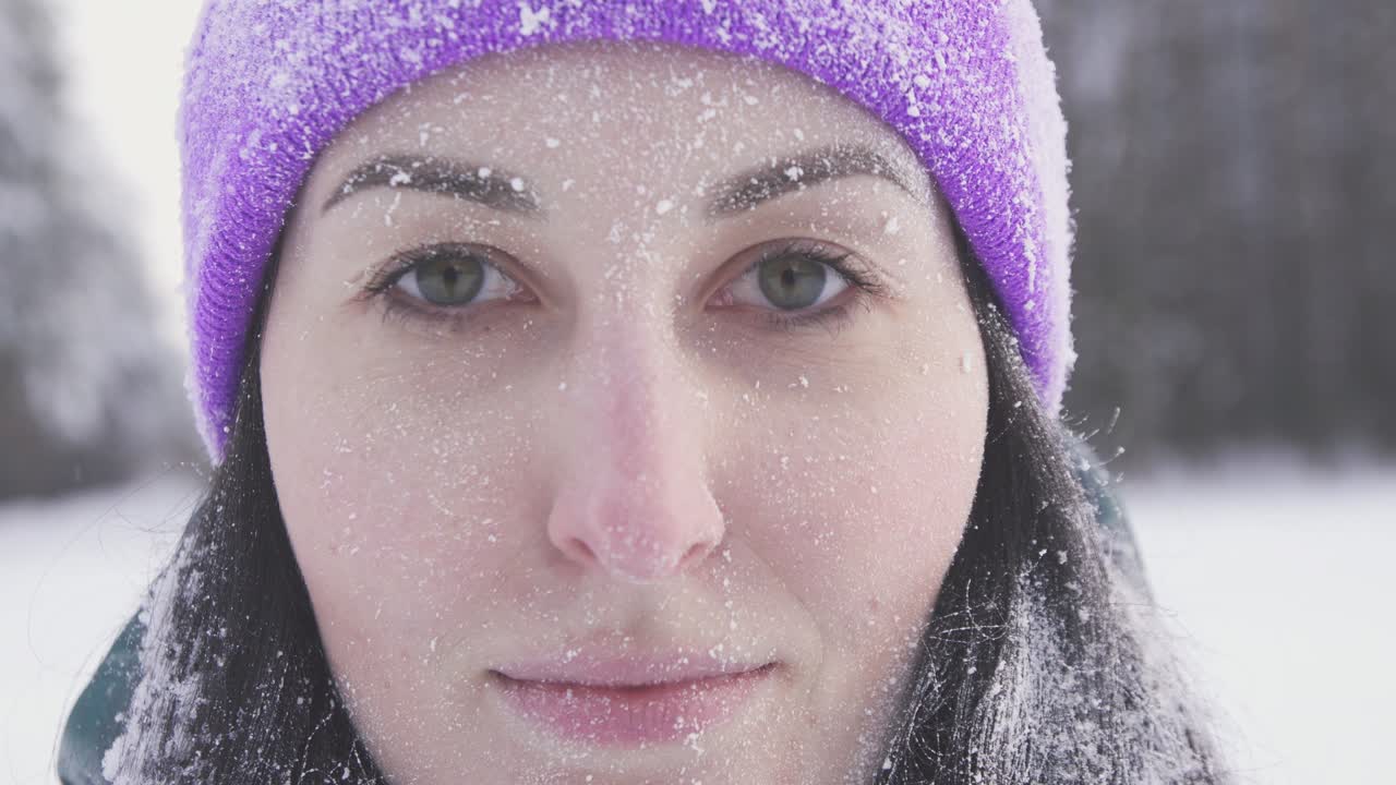 lonely girl in the woods smiling looking at the camera, covered with snow