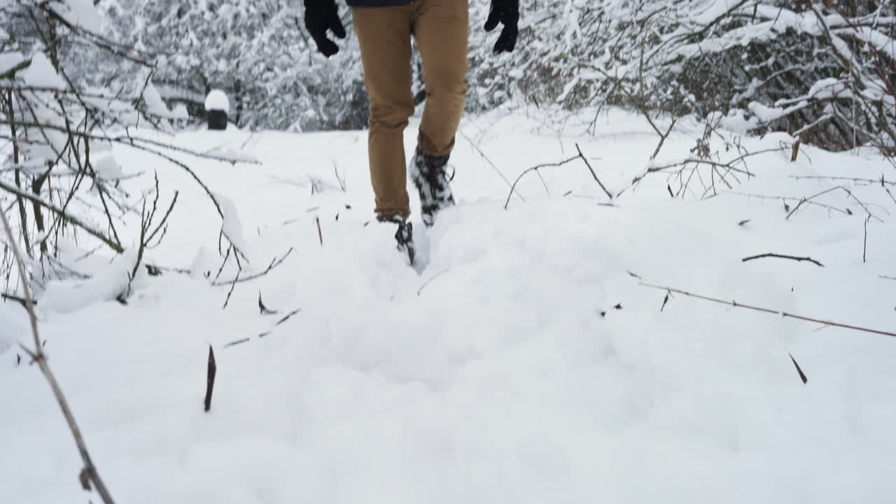 Man's feet walking in the snow during the day in wintertime in Bieszczady National Park, Subcarpathian Voivodeship, Poland, medium shot, handheld