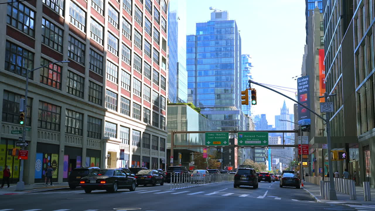 New York, USA, 9 August 2025: Cars driving through modern Manhattan streets. Traffic flows through a wide street in Manhattan surrounded by tall glass buildings and bright city lights
