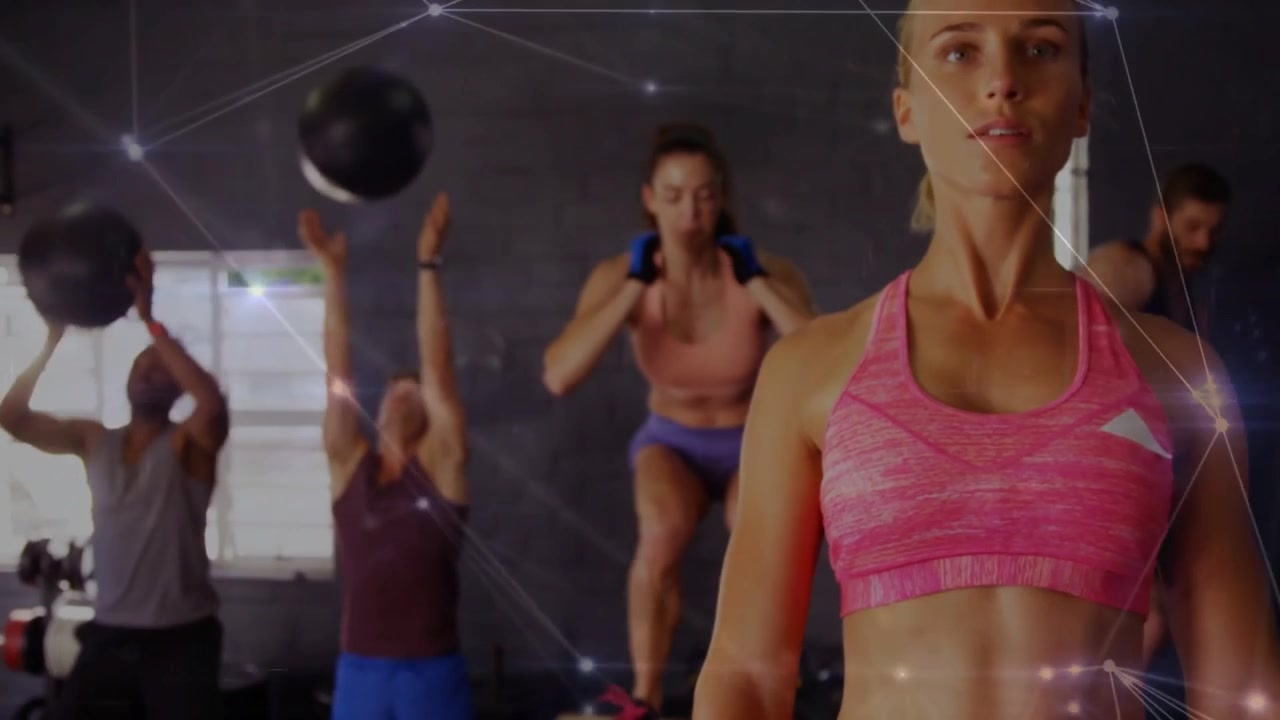 Coach geeft aanwijzingen, leidende vrouw leidt fitnesscircuit, medicijnballen vliegen met netwerkoverlay.