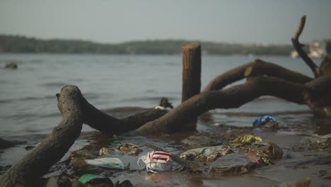 a polluted river bank along the mandovi river covered in litter, trash and rubbish discarded by people, panjim, india