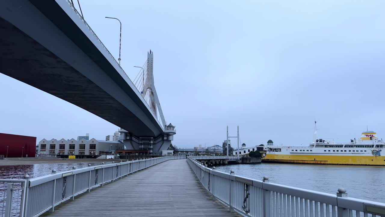 Overcast morning view of Aomori Bay with bridge, ferry and calm waterside walkway