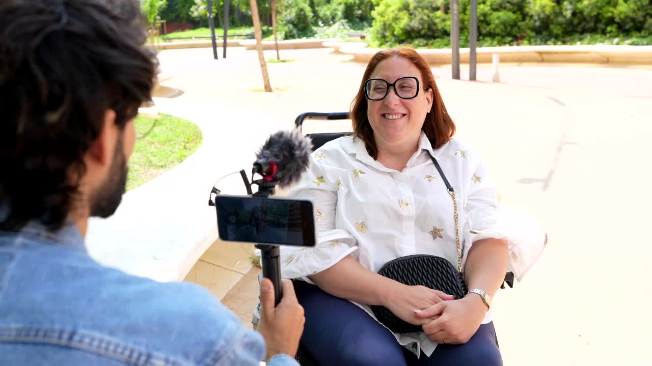 Woman in Wheelchair Being Interviewed for a Vlog in a Park