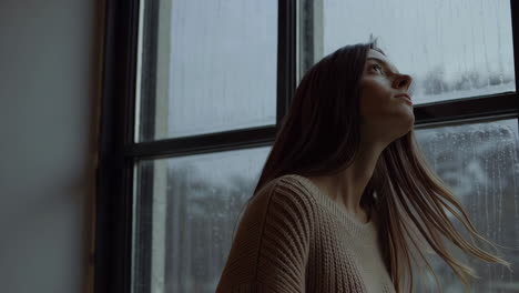 woman looking out a rainy window